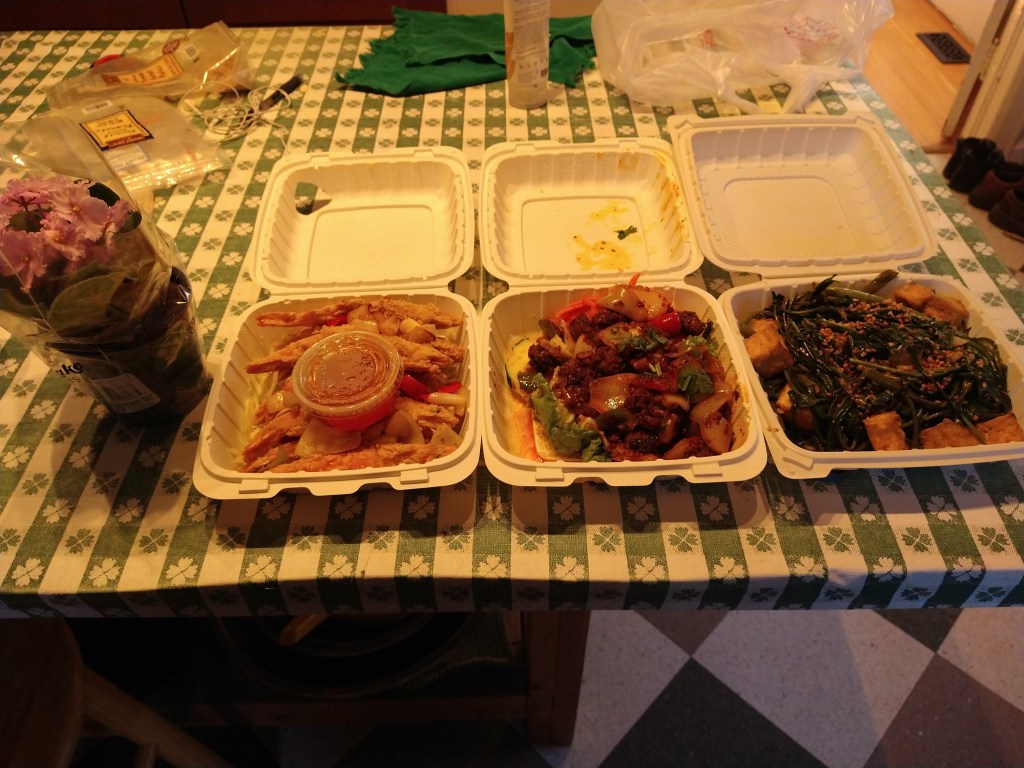 Takeout food from Rainer Restaurant tonight. From right to left: Salt and Pepper Prawns, Sizzling Pepper Eel (the first time I have had cooked eel before), and Stir Fried Garlic Ong Choy. Also shown is a pink flower in a plastic planting pot.
