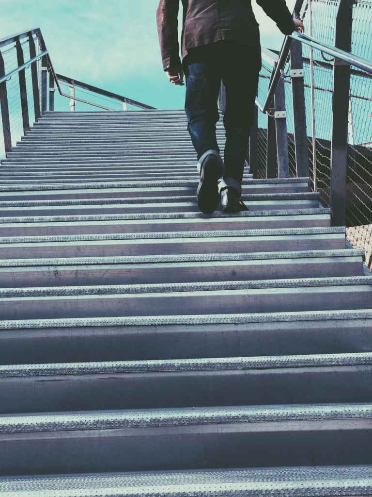 Man outside waking stairs to a bridge