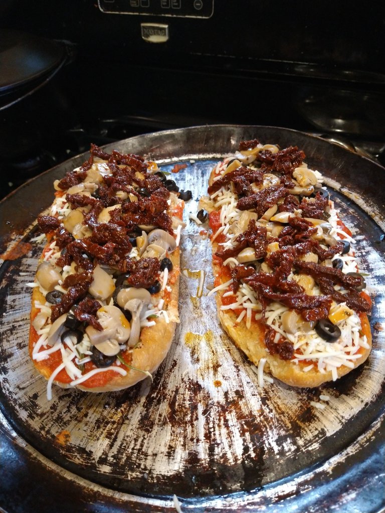 Add half the cheese, then one at a time layer the olives, mushrooms, and sundried tomatoes to the tomato sauce bread.