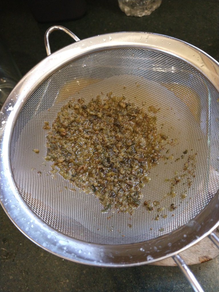 Picture of strained cannabis solids in a fine mesh strainer.
