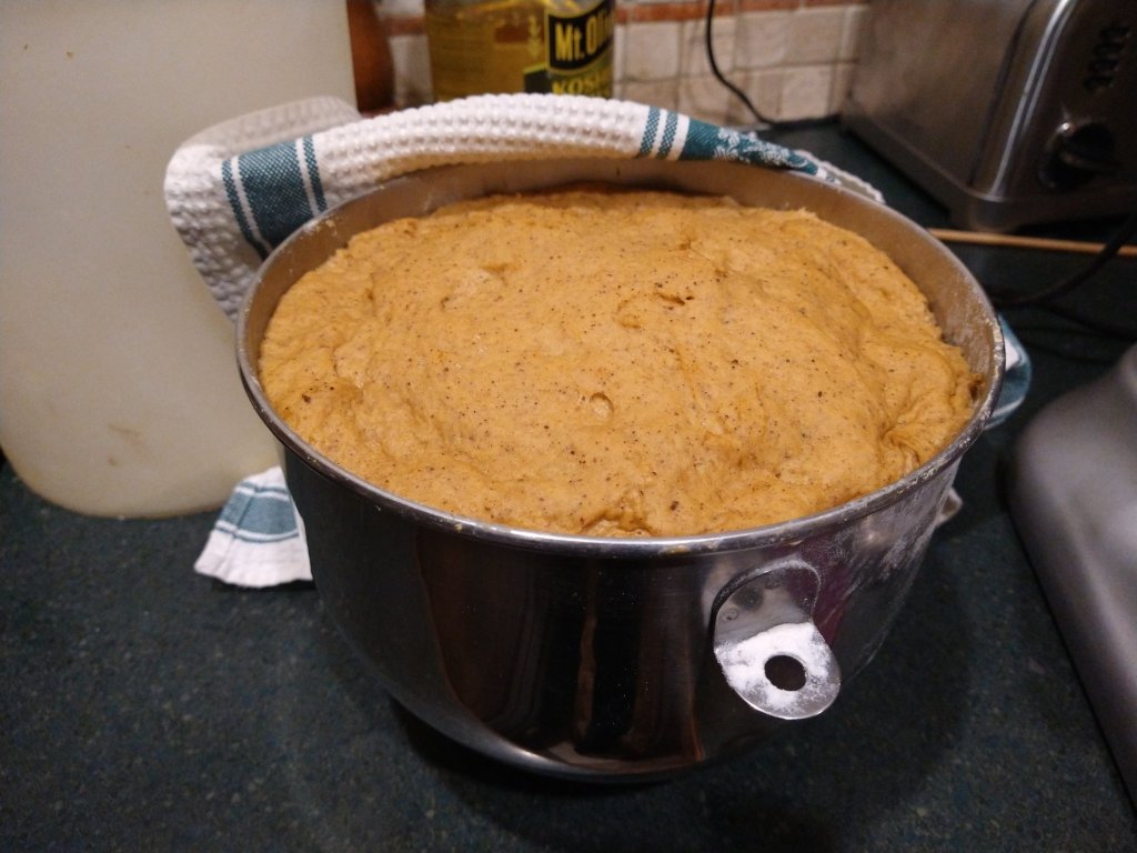 pumpkin spice cinnamon roll dough doubled in size in a kitchen air bowl.