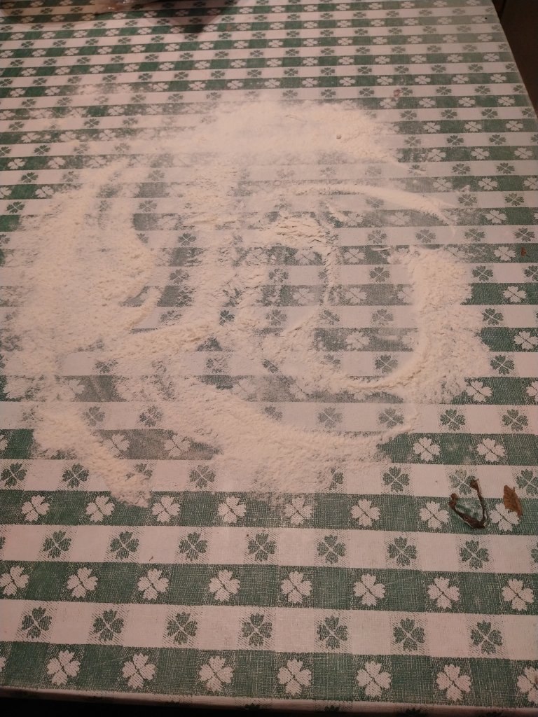 Picture of flour strewn on a table as a step to kneading cinnamon roll dough.